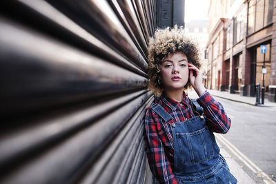 Portrait of beautiful young woman standing against built structure