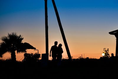 Silhouette people against clear sky at sunset