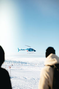 Rear view of people with airplane flying in sky