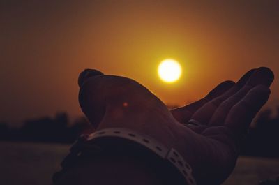 Low section of person against orange sky during sunset