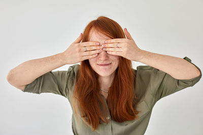 Close-up of young woman closing eyes against white background