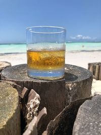 Close-up of drink on table at beach against sky