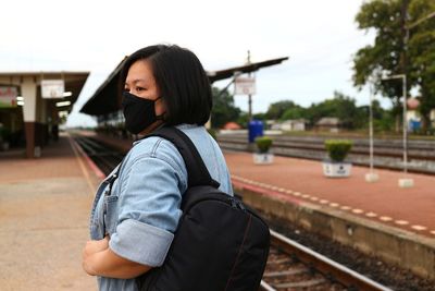 Side view of young woman standing at railroad station