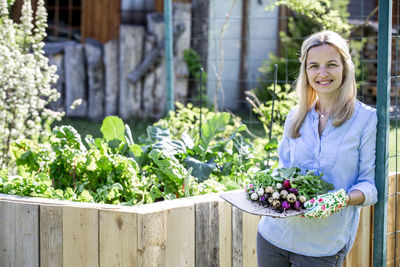 Portrait of mid adult woman holding radishes at farm