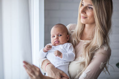 Smiling mother holding baby boy at home