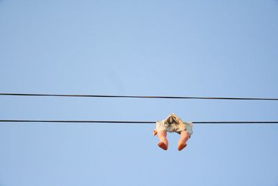 Low angle view of toy hanging from cable against clear sky