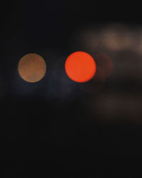 Defocused image of illuminated lights against sky at night