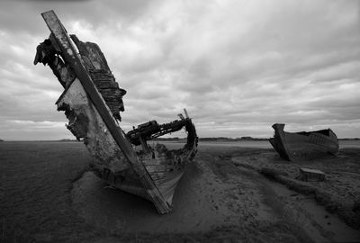 Abandoned boat on beach against sky