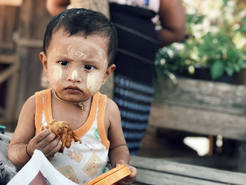 Portrait of cute baby girl holding food while sitting outdoors