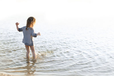 Rear view of girl standing in sea