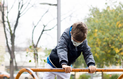 Little boy wearing protective face mask while playing on the playground.