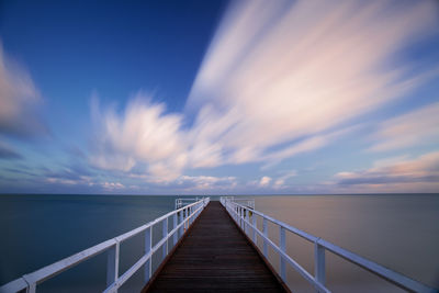 Pier over sea against cloudy sky