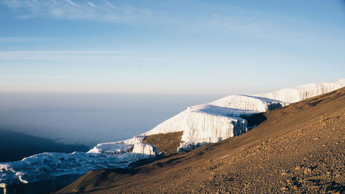 Snow on mountain by sea against sky