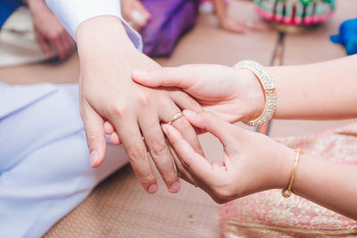 Cropped image of bride putting ring on bridegroom during wedding ceremony