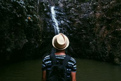 Man standing in front of waterfall in forest