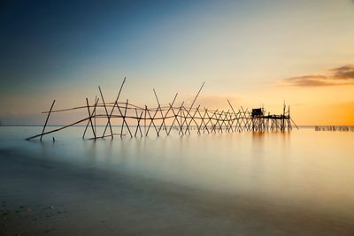 Silhouette cranes against sky during sunset