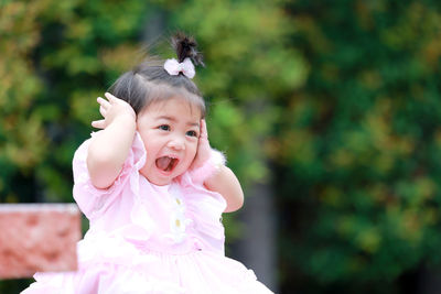 Sitting on the green grass, a lovely little girl wears pink fashionable clothing.