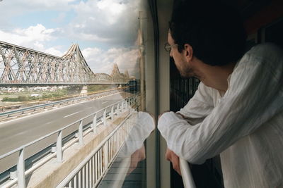 Man looking through window while standing in train