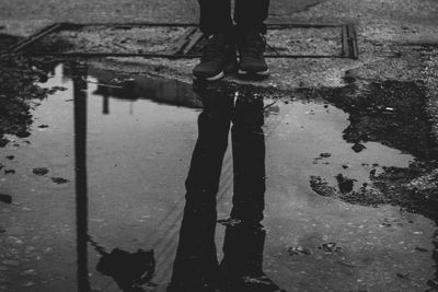 Low section of man standing on puddle