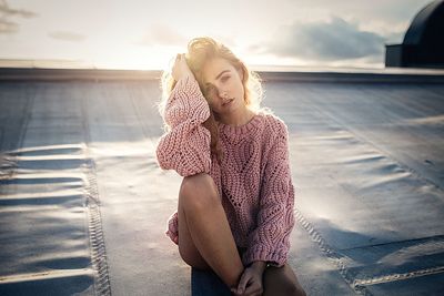 Portrait of young woman sitting against sky