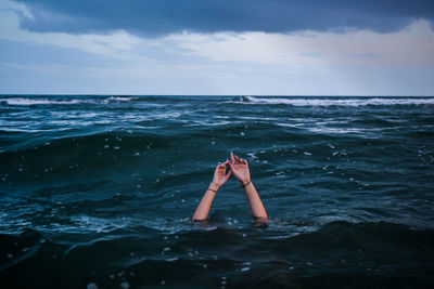 Low section of woman swimming in sea against sky
