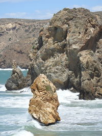 Rock formation on beach against sky