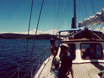 People on sailboat sailing in sea against sky