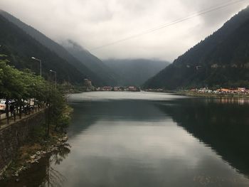 Scenic view of river by mountains against sky