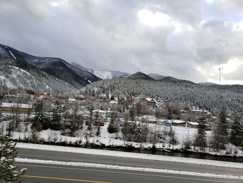 Snow covered road by mountains against sky