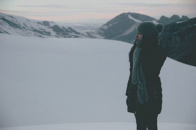 Woman standing on snow during sunset