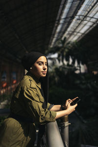 Portrait of young woman standing against building