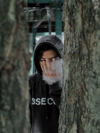 Portrait of mid adult man standing by tree trunk