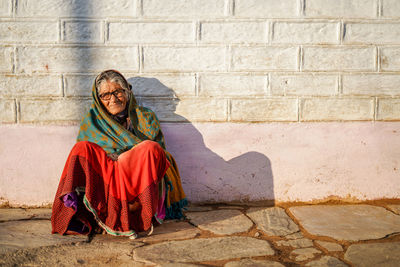 Full length of woman sitting against wall