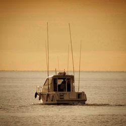 Boats sailing in sea at sunset