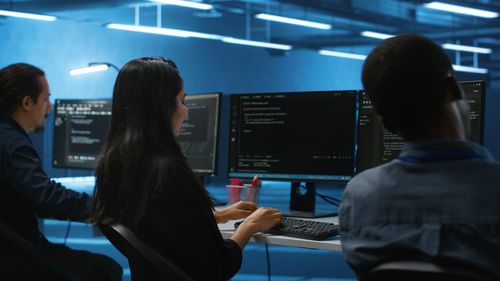 Rear view of young woman using mobile phone in office