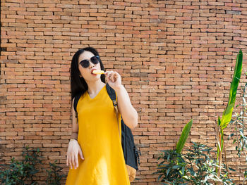 Full length of woman standing against brick wall