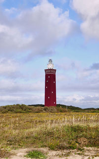 Lighthouse on field against sky