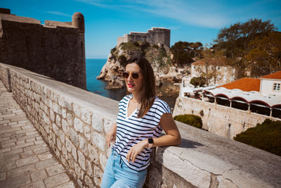 Portrait of young woman standing against wall