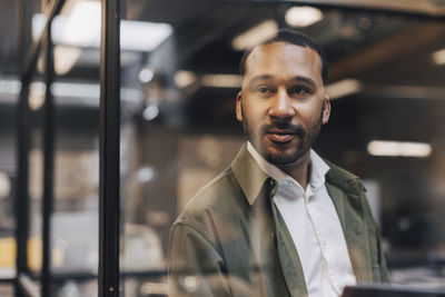 Thoughtful businessman standing in illuminated office