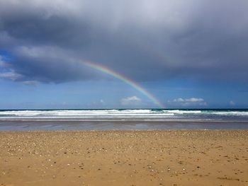 Scenic view of rainbow over sea against sky