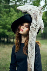 Portrait of young woman standing against trees