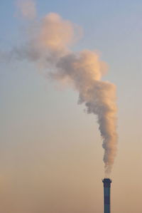 Smoke emitting from chimney against sky