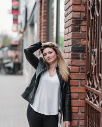 Portrait of young woman standing against wall