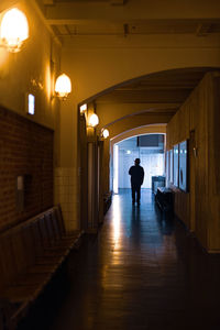 Rear view of silhouette man standing in corridor of building
