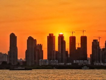 Modern buildings in city against orange sky