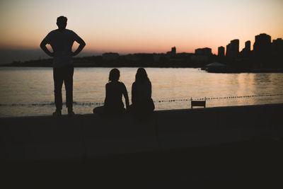 Silhouette people against sea during sunset