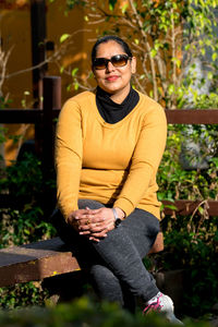 Portrait of a young woman with sunglasses sitting on a bench