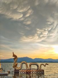 Statue of bridge over sea against cloudy sky