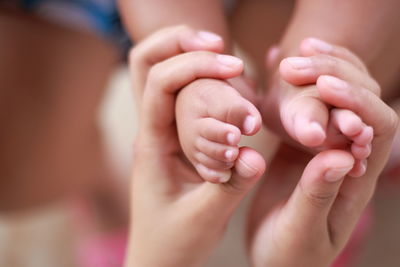 Cropped hands of mother holding baby legs