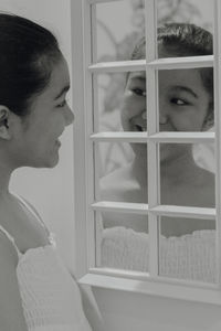 Close-up southeast asian teenage girl looking at herself and smiling in the mirror 